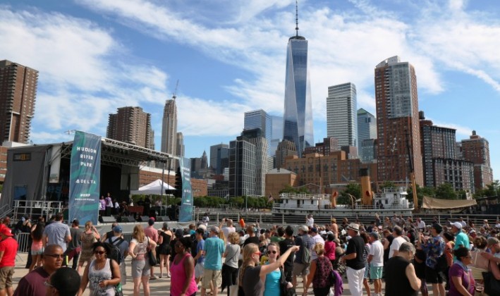 group of people gathered at hudson river bbq festival with city skyline in background